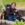 A woman with a bright, sunny smile rides in a wheel chair in an outdoor garden.